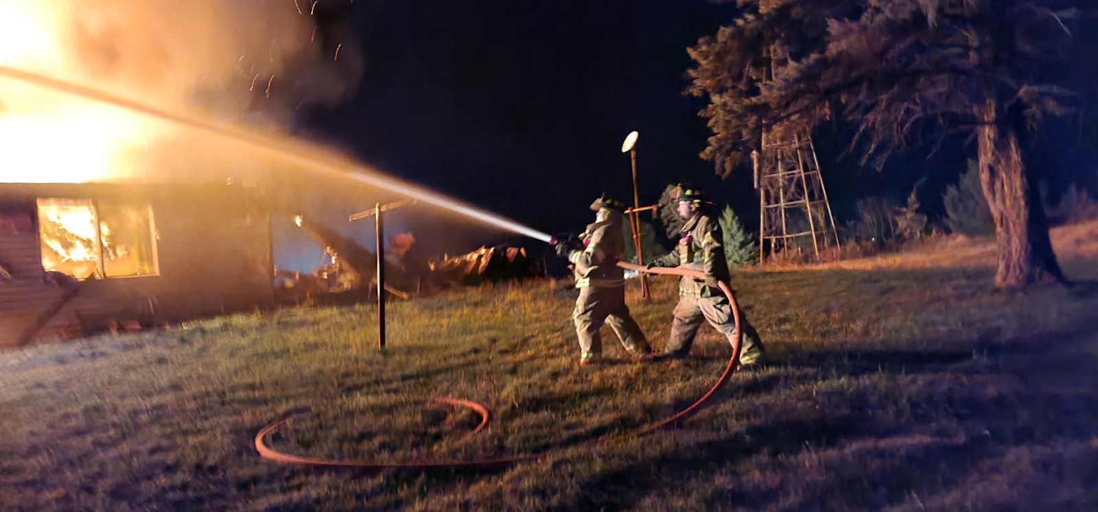 Firefighter with hose fighting house fire